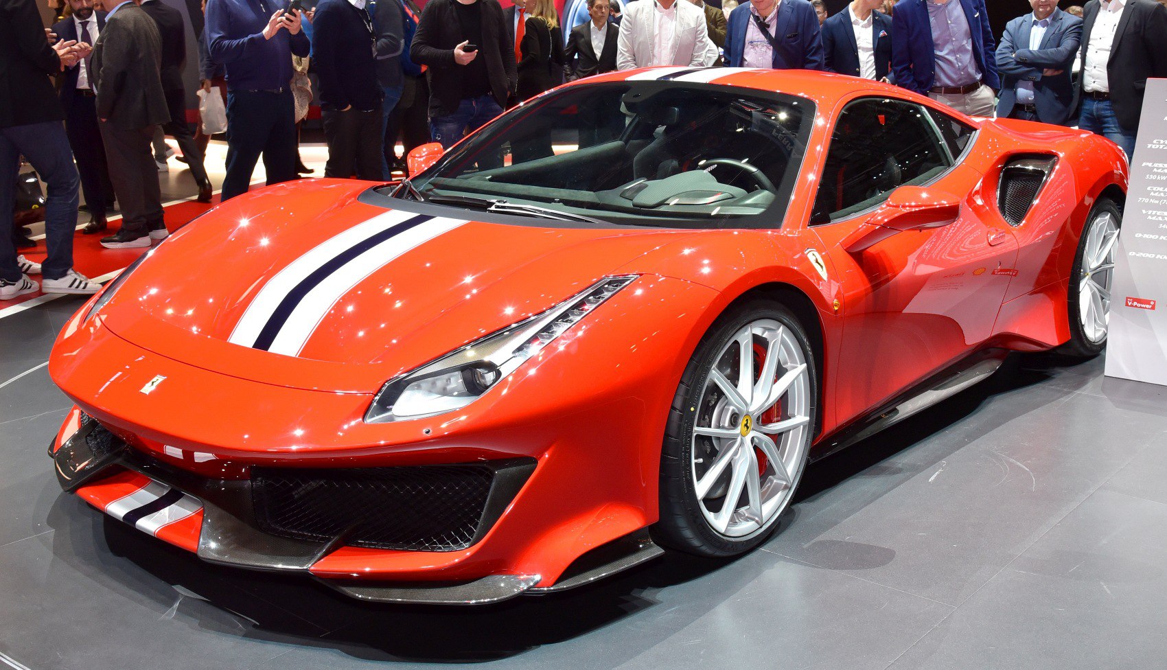 Front angled view of a sleek red sports car with racing stripes