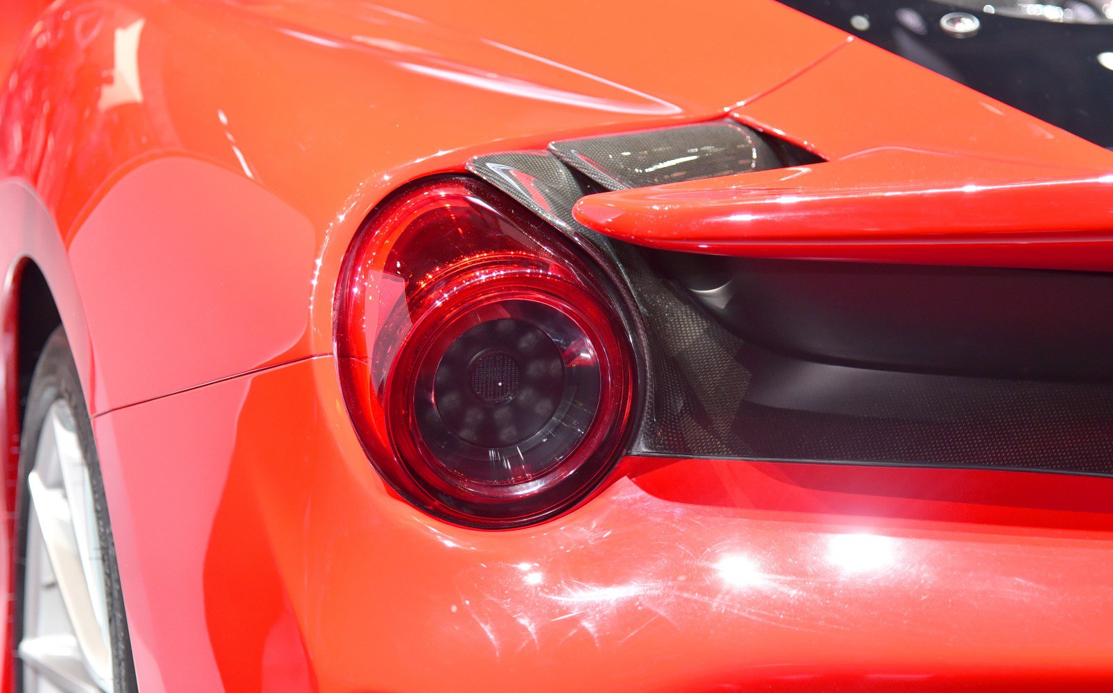 Round rear tail light with carbon fiber detail on red sports car
