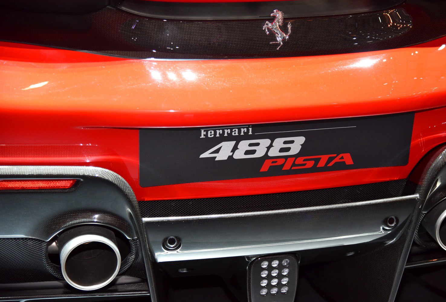 Close-up of car rear exhaust, carbon fiber diffuser, and brand badge