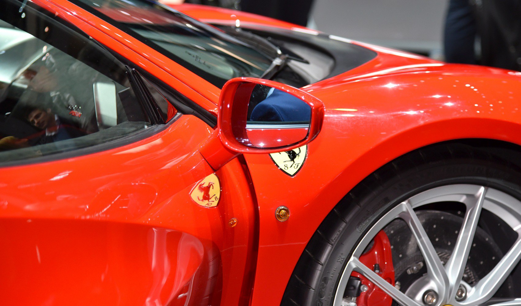 Red side mirror with Ferrari badges and alloy wheel