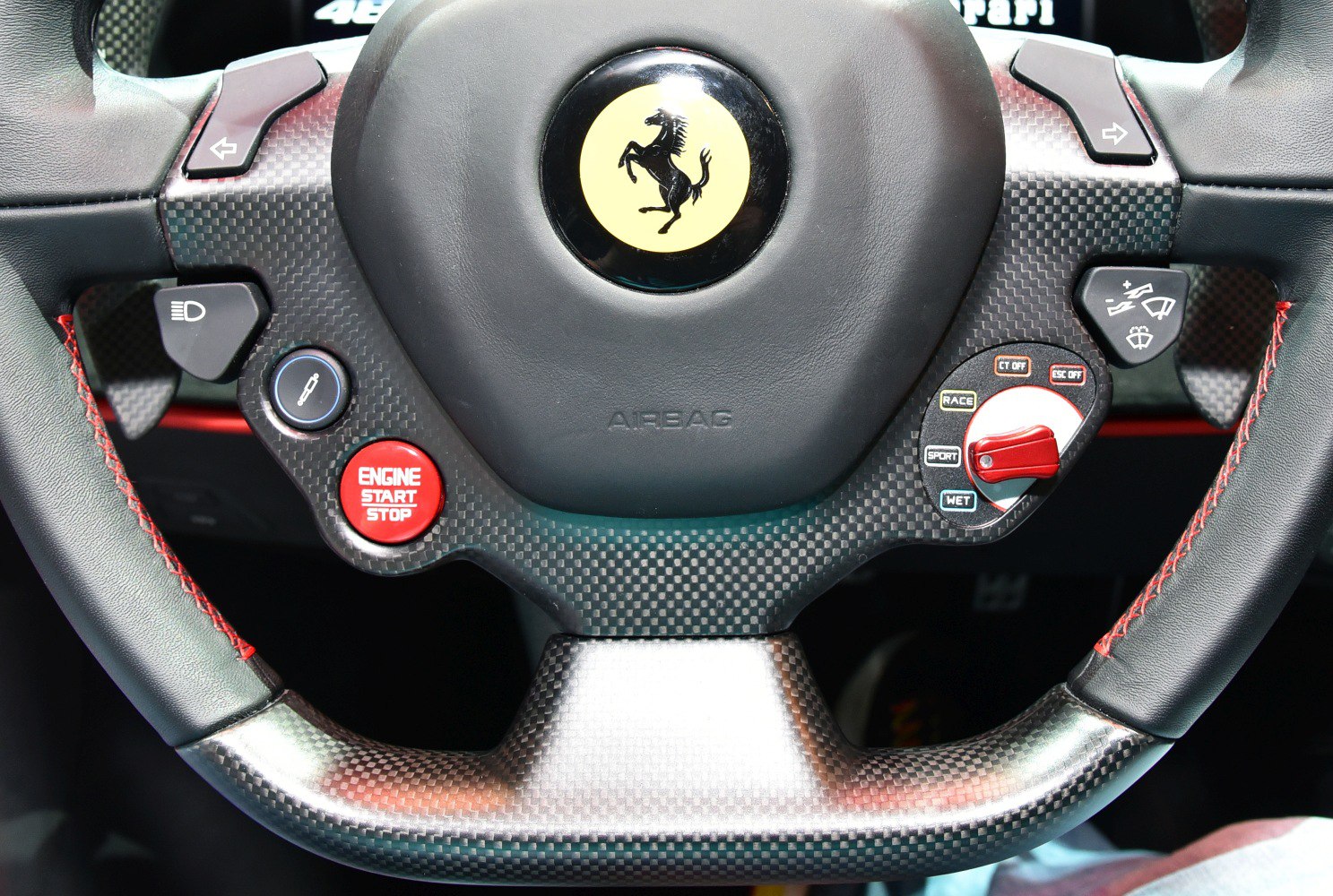 Carbon fiber steering wheel with control buttons and prancing horse emblem