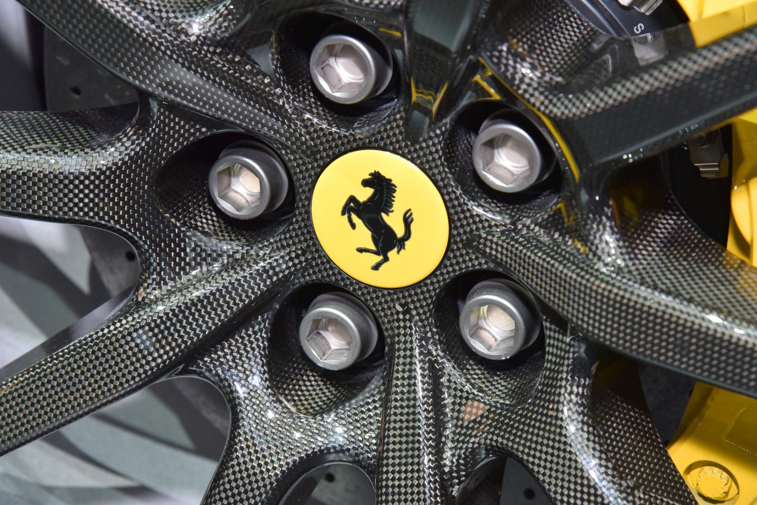 Close-up of carbon fiber alloy wheel with yellow Ferrari emblem