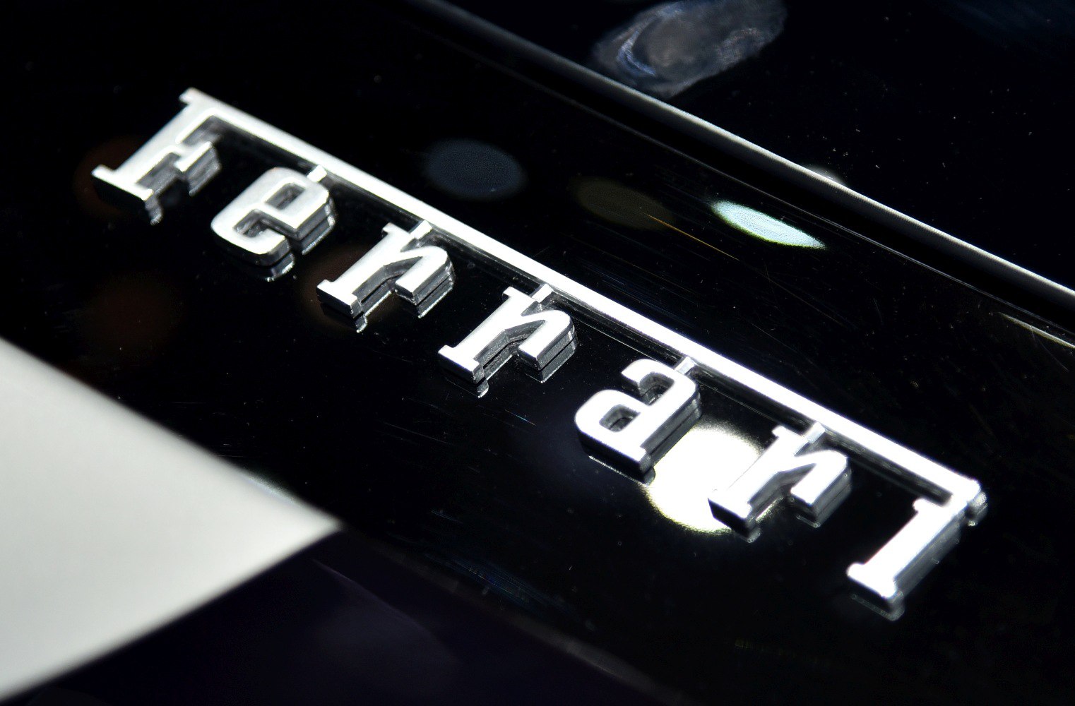 Close-up of shiny silver Ferrari logo emblem on black surface