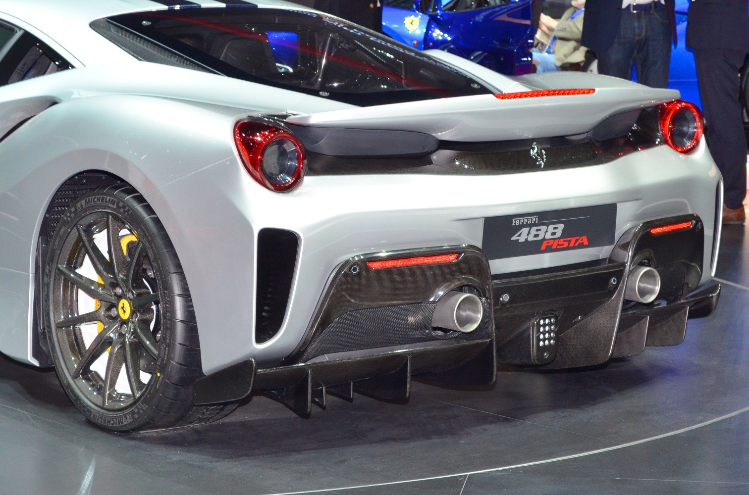 Rear view focusing on dual exhausts, round taillights, carbon fiber diffuser, and rear wheel.