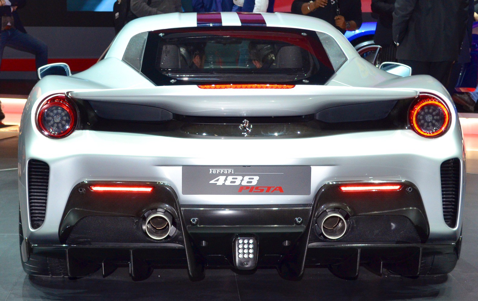 Rear view with illuminated circular taillights, dual exhaust, and prominent diffuser.