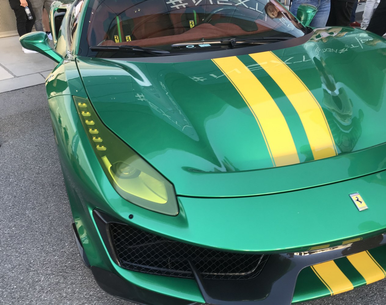 Green supercar front with yellow racing stripes and aerodynamic grille