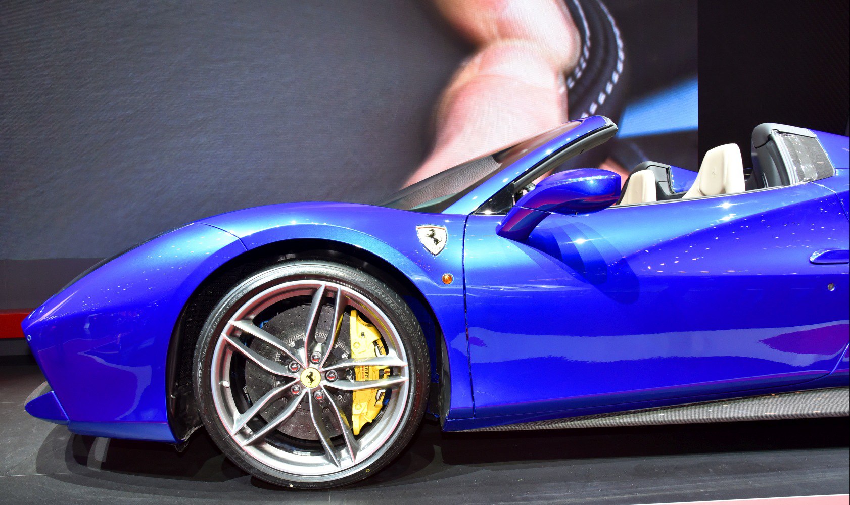 Front side and wheel of blue convertible sports car with yellow brake calipers