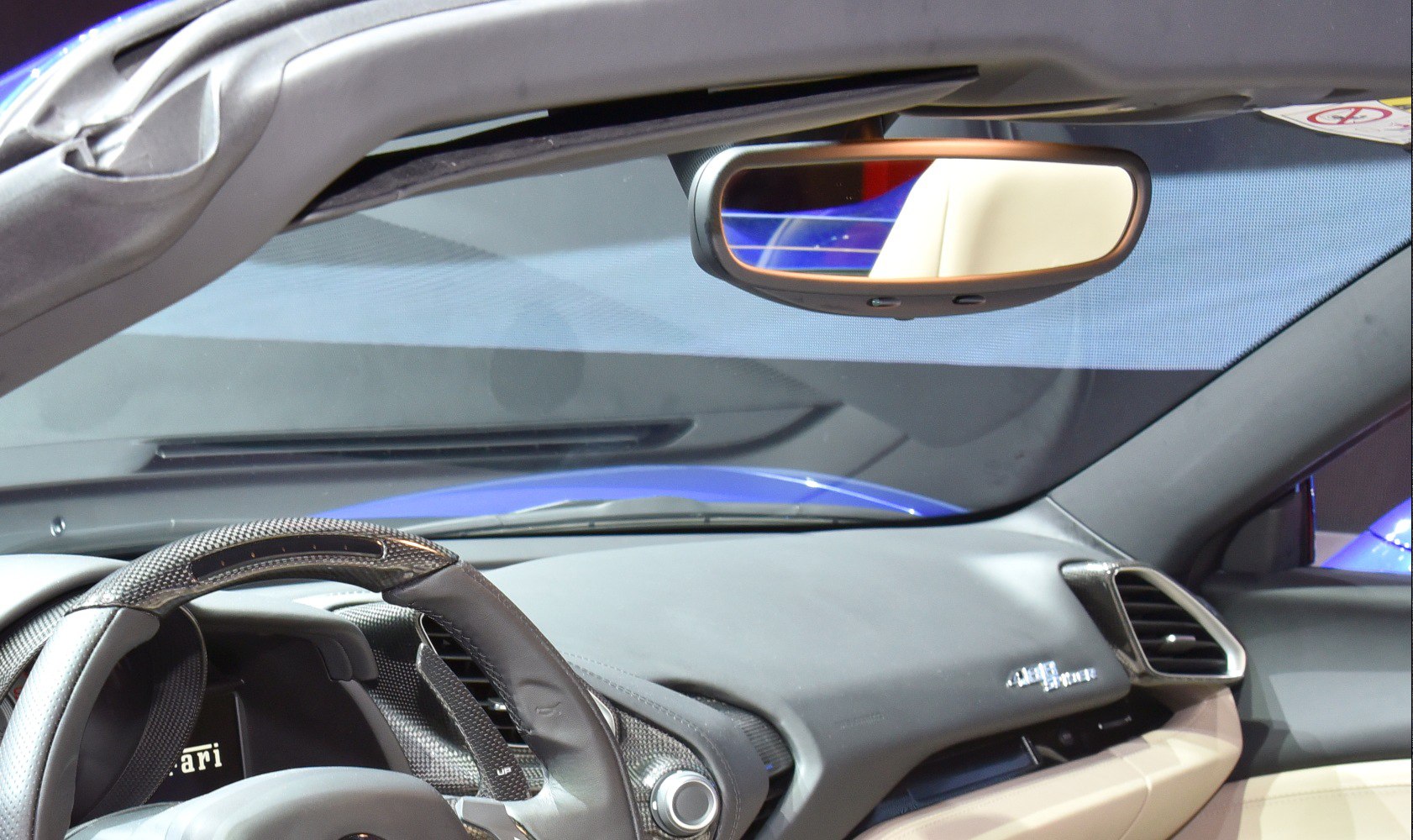 Luxury car interior with carbon fiber steering wheel and detailed dashboard.