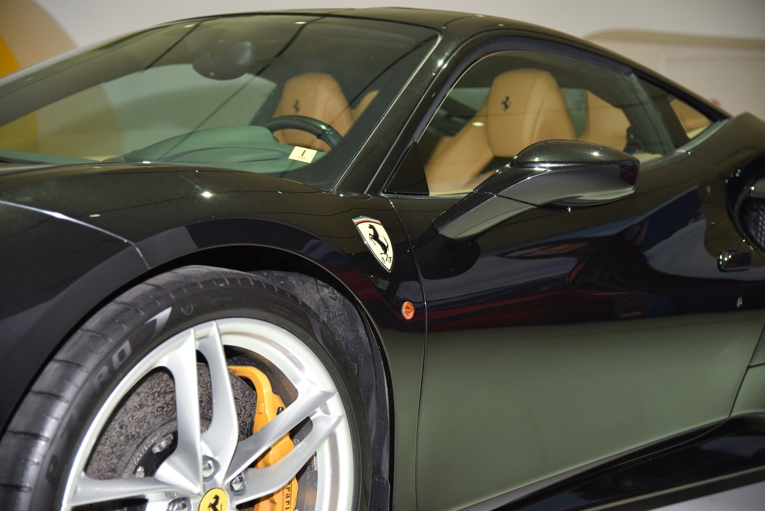 Close-up of front wheel, side mirror, and tan leather interior