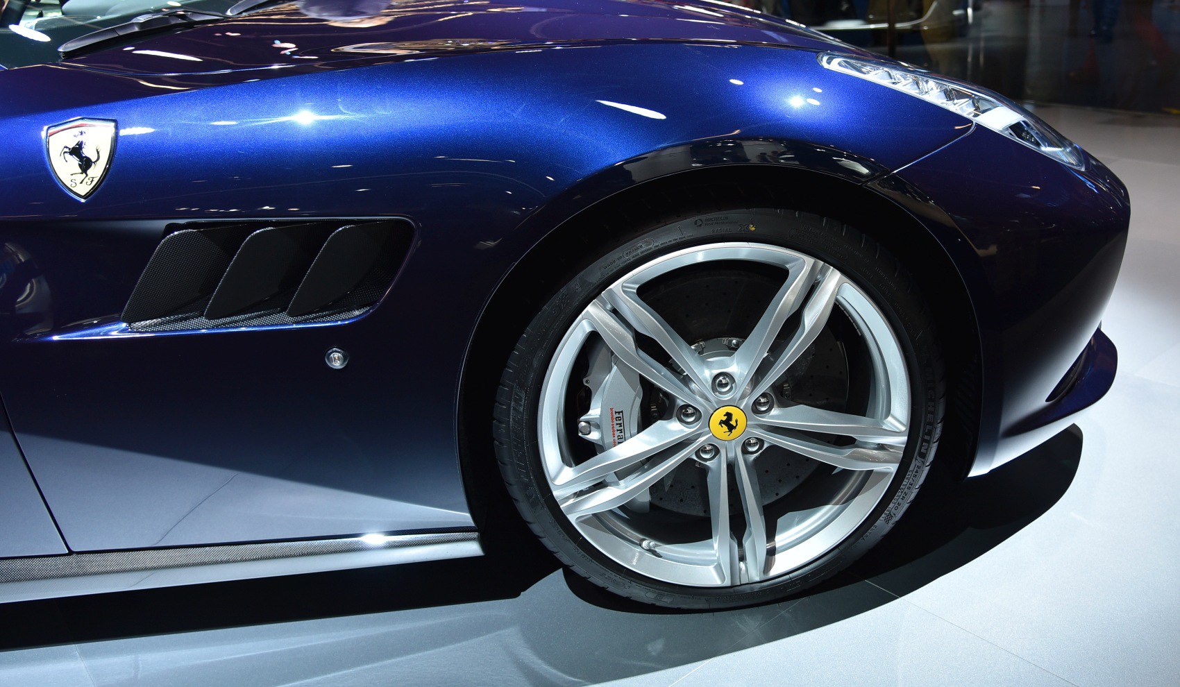 Close-up of alloy wheel and air vent on blue sports car body