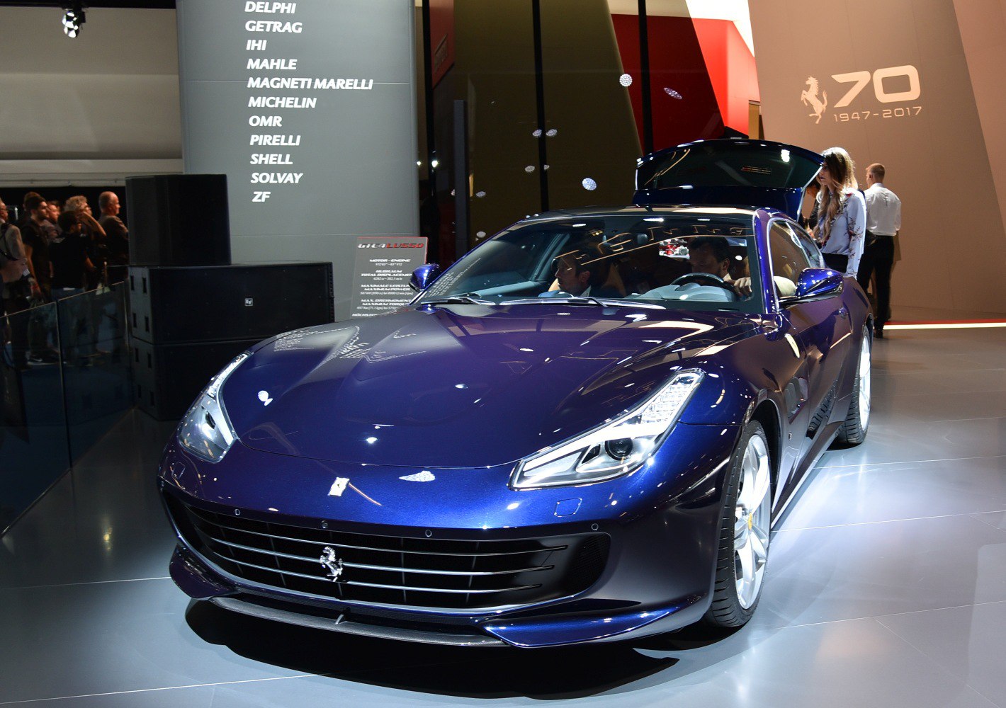 Front view of a blue sports coupe with LED headlights and rear trunk open