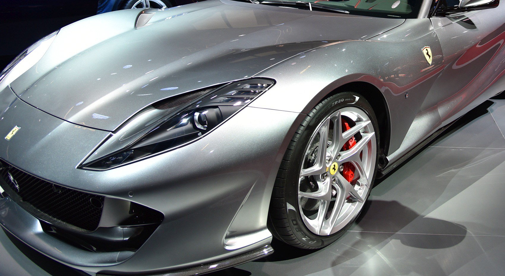 Close-up of front headlight and alloy wheel with red brake caliper
