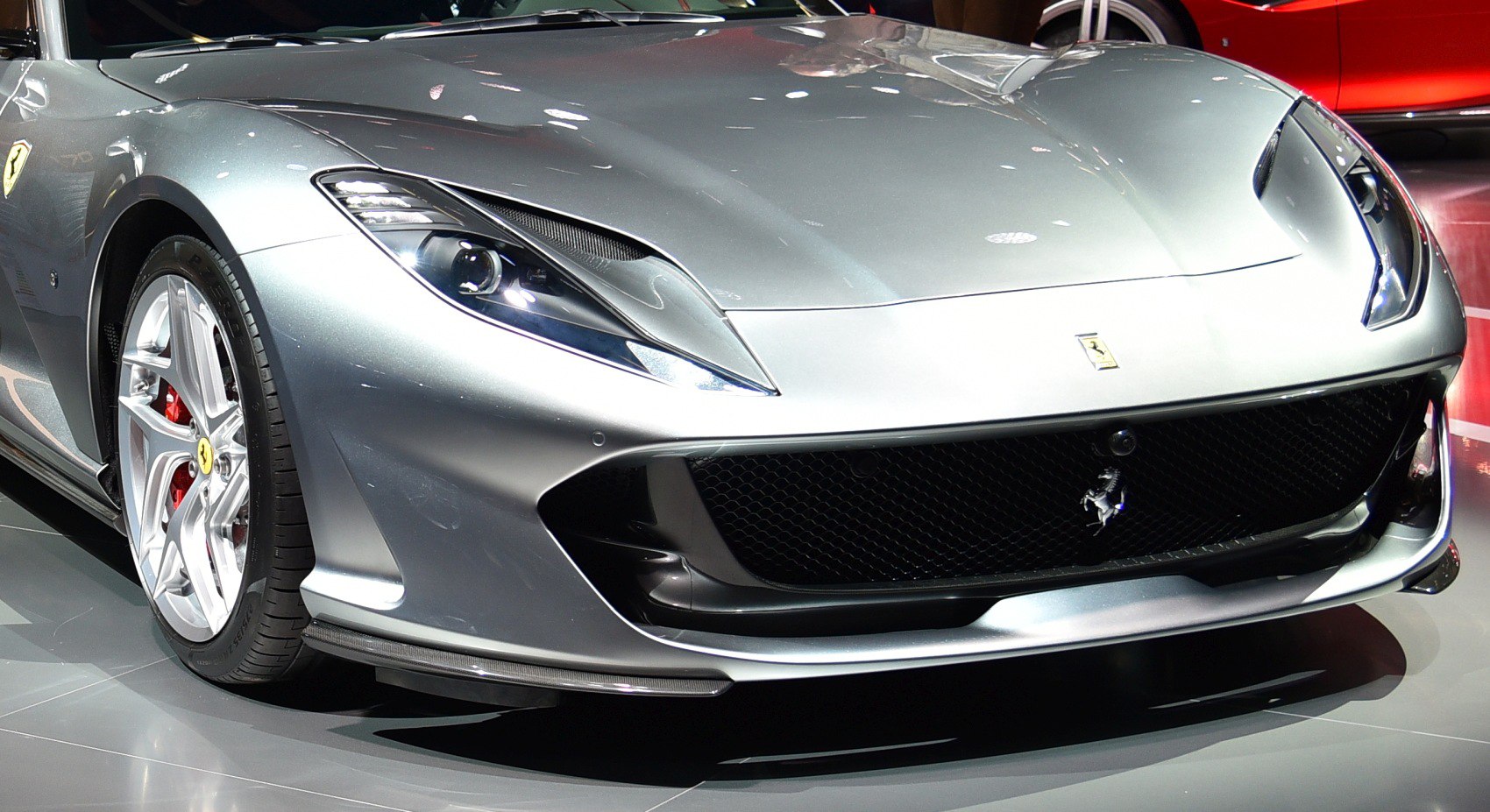 Close-up of front grille, headlights, and alloy wheel with red brakes