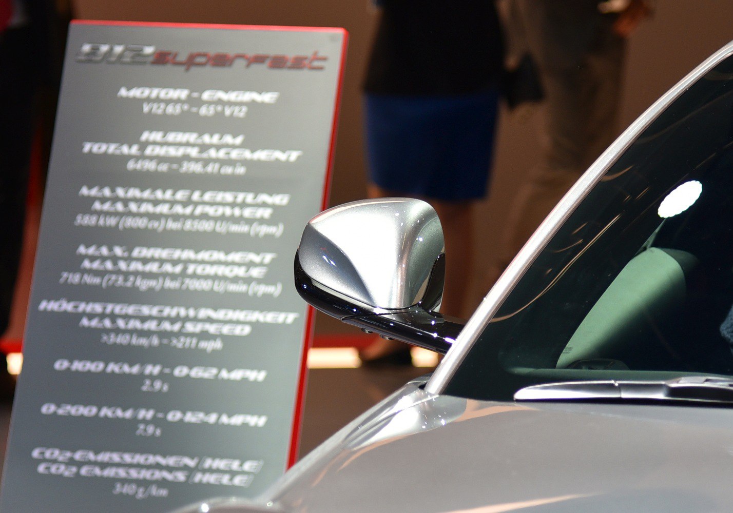 Close-up of a sleek side mirror with technical specs board in background