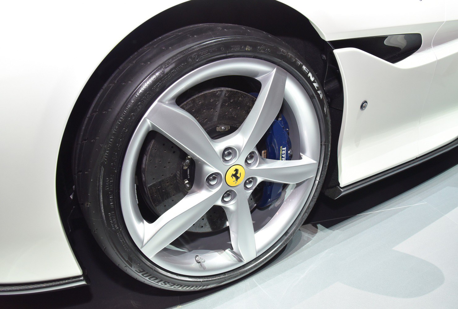 Five-spoke alloy wheel with blue brake caliper and drilled disc brake
