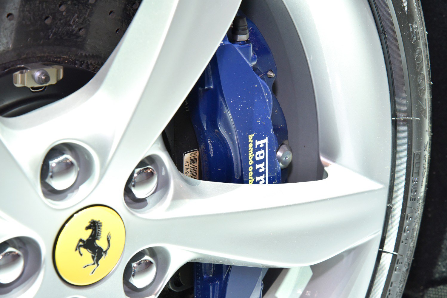 Close-up of silver alloy wheel and blue Brembo brake caliper