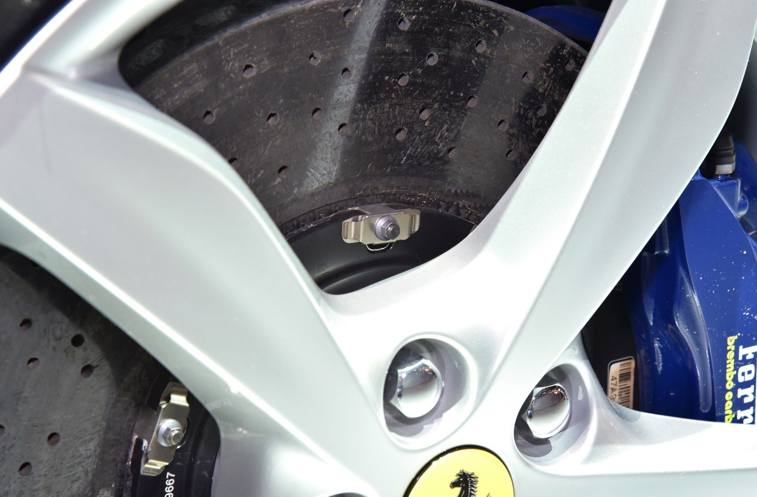 Close-up of drilled brake disc with alloy wheel and blue brake caliper