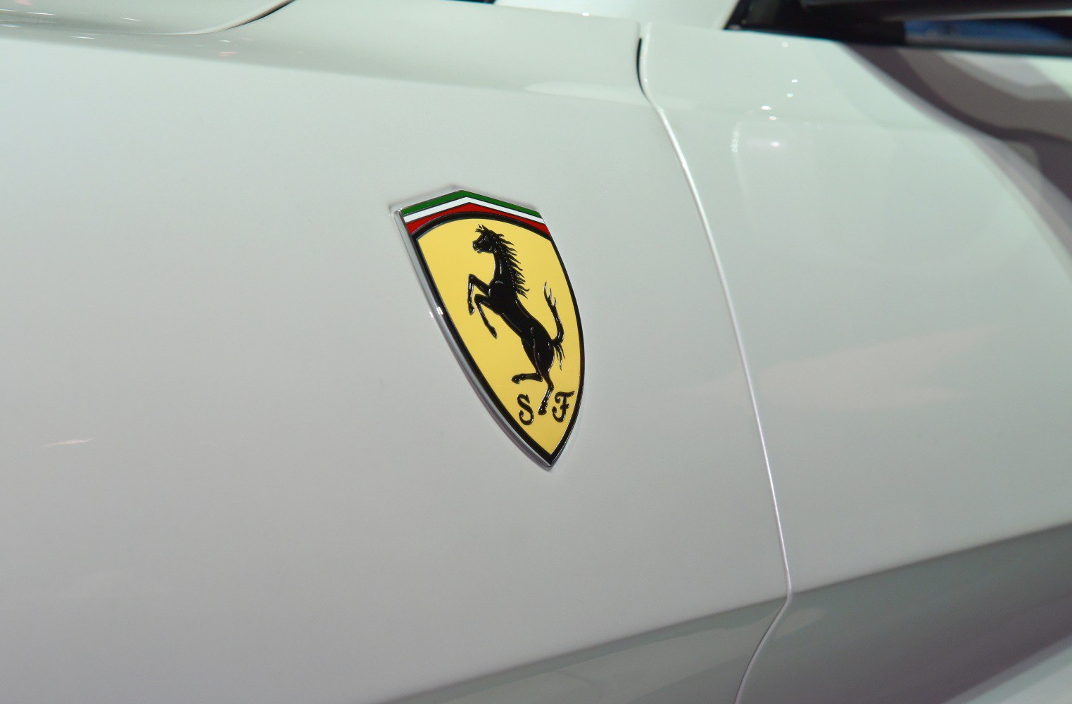 Close-up of Ferrari prancing horse side badge on white car surface