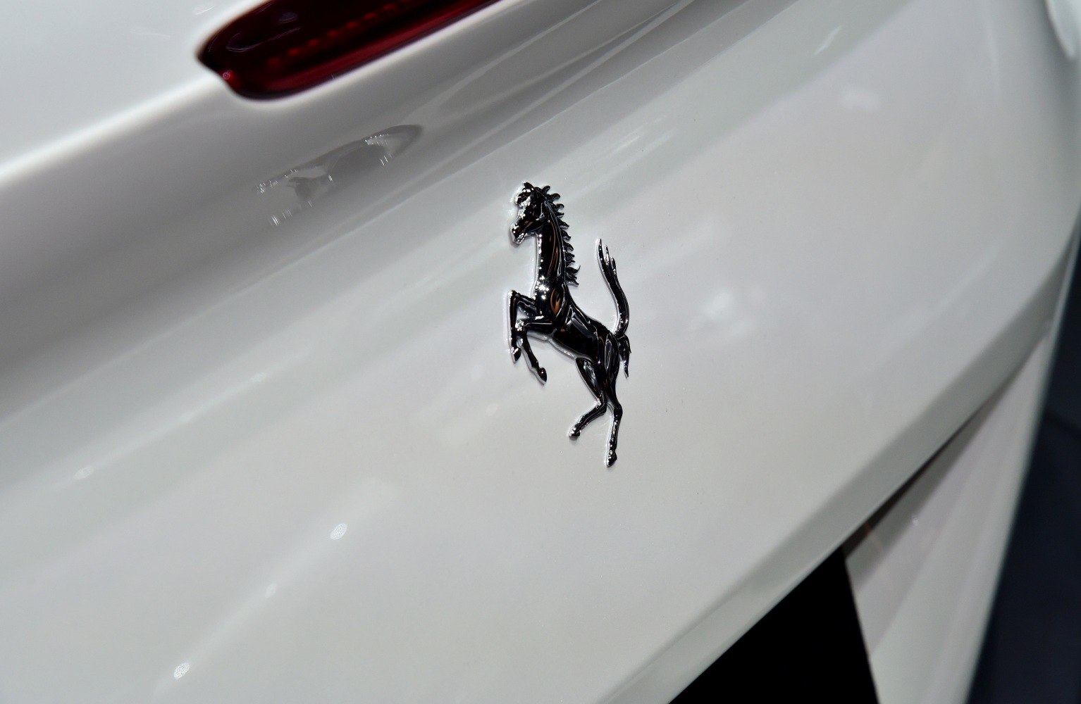 Close-up of black prancing horse emblem on a white glossy surface