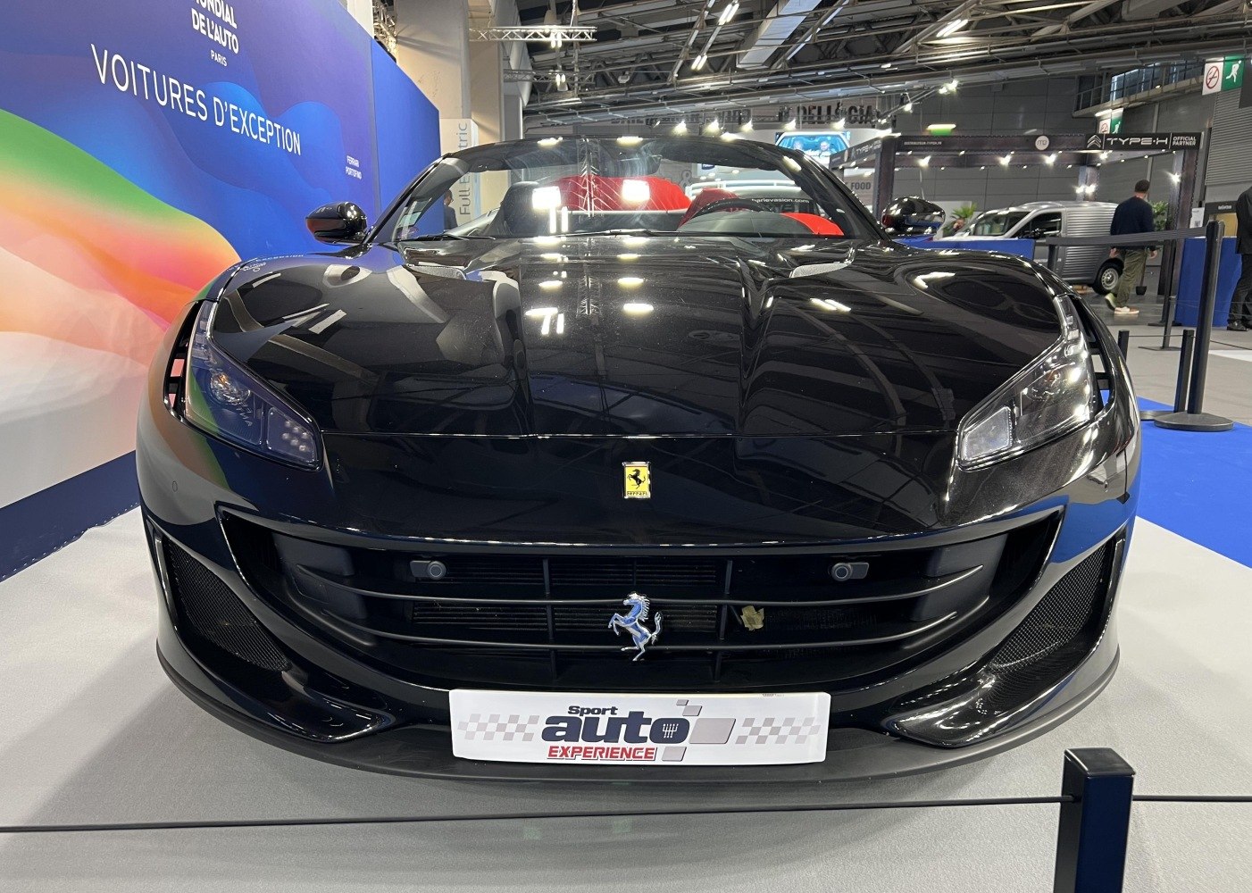 Close-up front view of black luxury convertible with distinct headlights and grille
