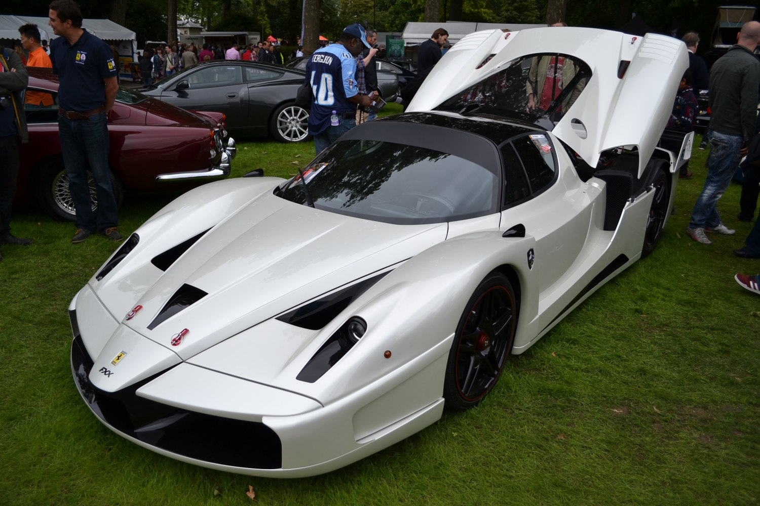 White exotic racing car with open rear engine cover and sleek aerodynamic design.