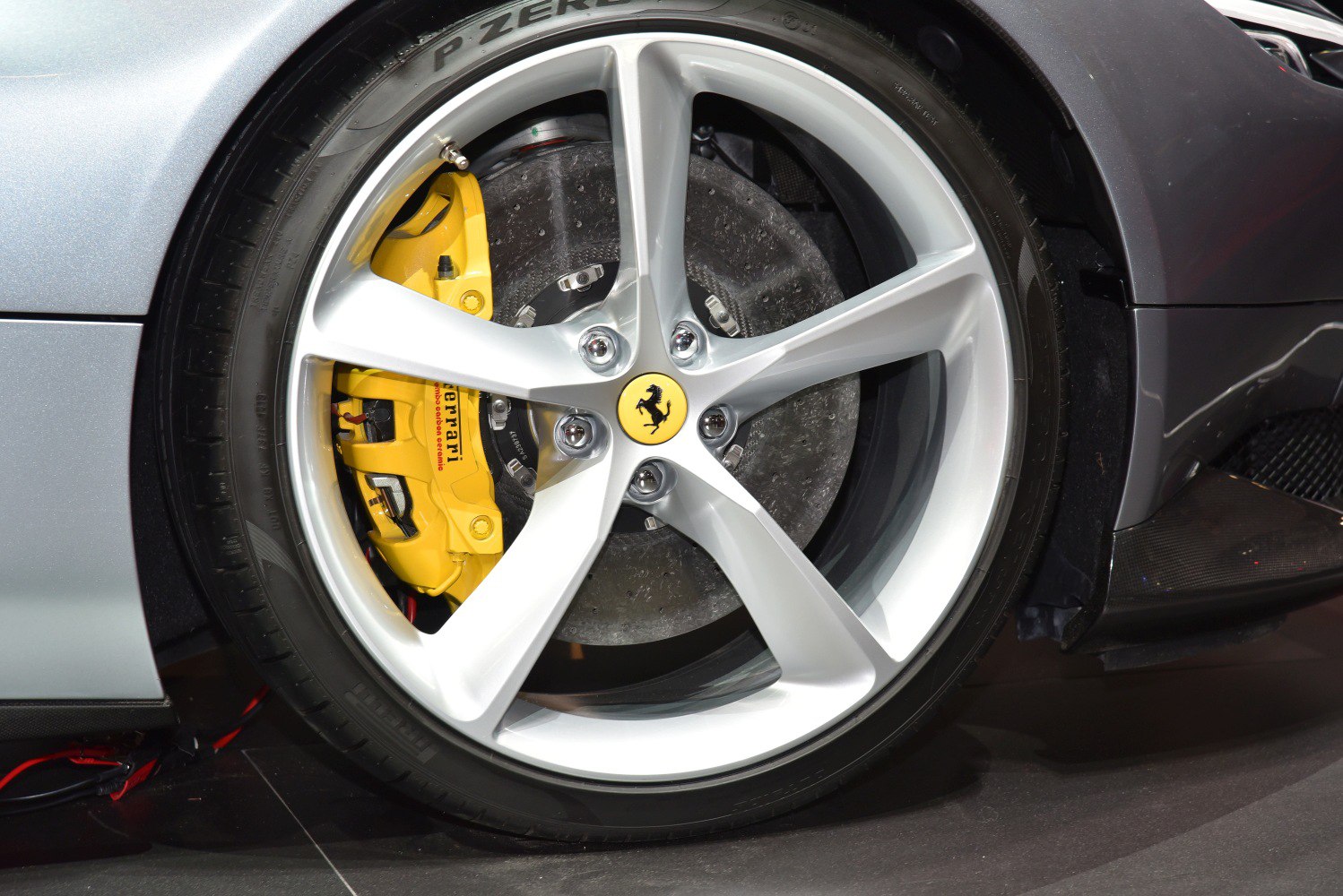 Silver alloy wheel with yellow brake caliper and Ferrari emblem
