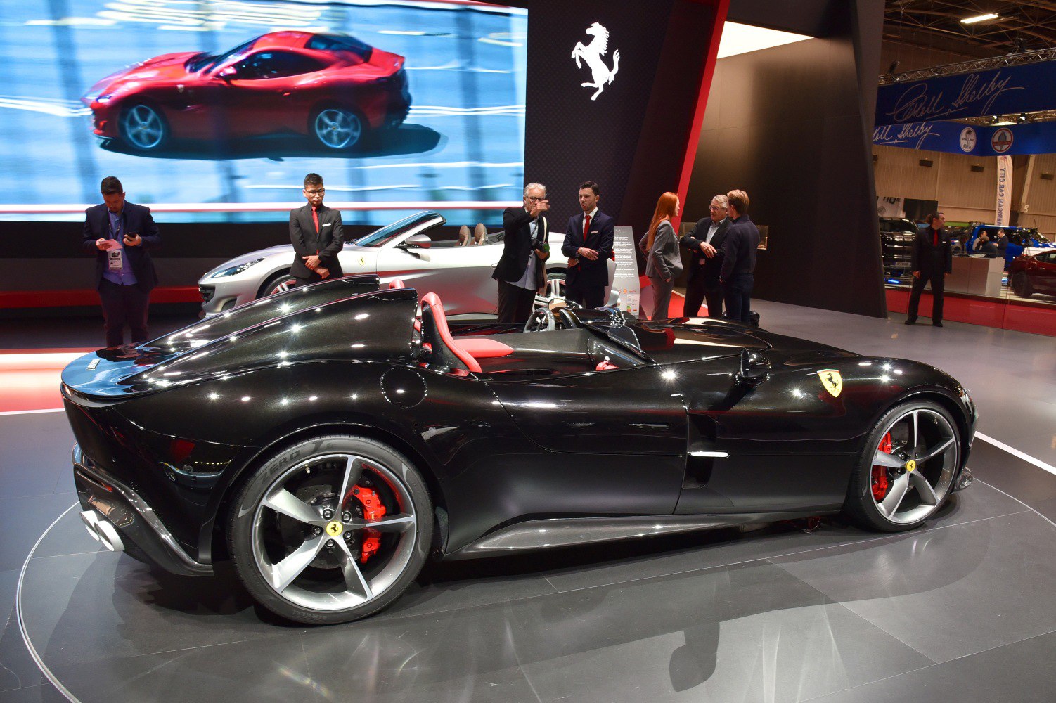 Black two-seat open-top sports car with red interior and distinct rear design