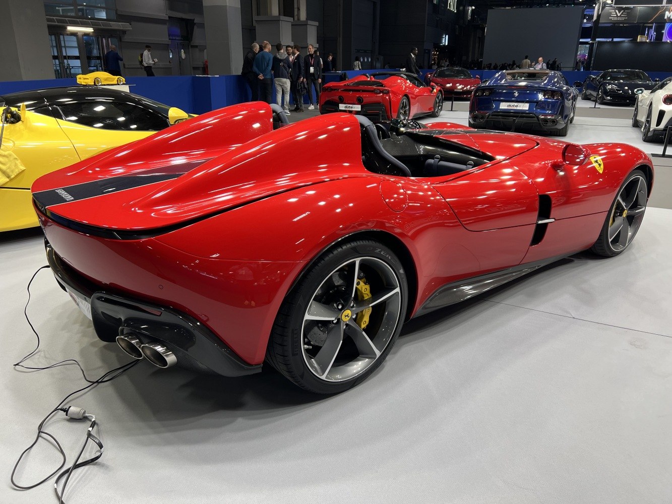 Twin cockpit red supercar with aerodynamic rear side and large wheels.