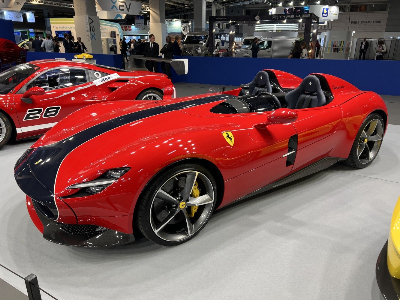 Open-top sports car with black racing stripe and two-seater cockpit.