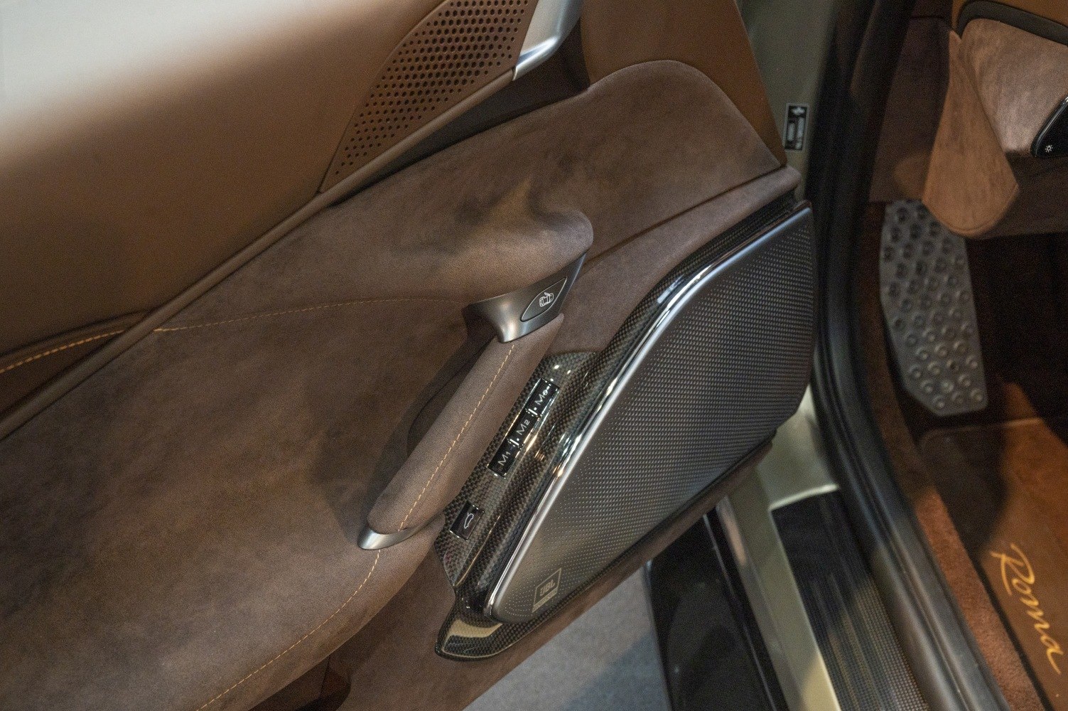 Brown Alcantara door panel with carbon fiber trim and audio speaker