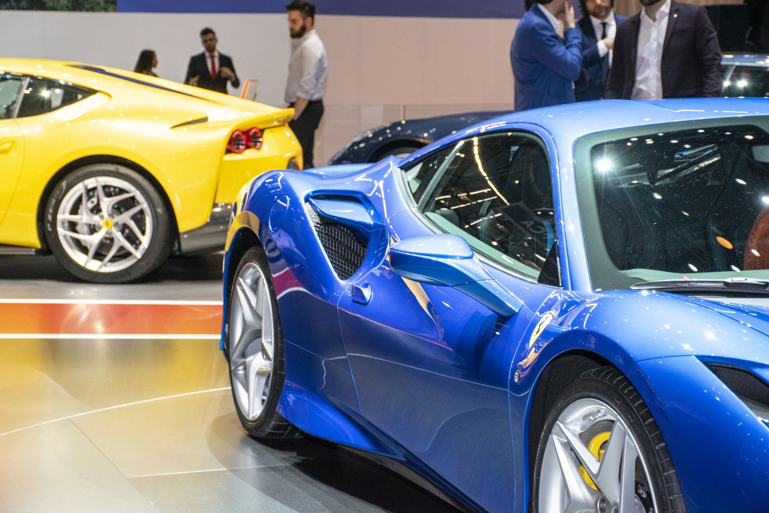 Side air intakes, alloy wheels, and aerodynamic body design on two sports cars.