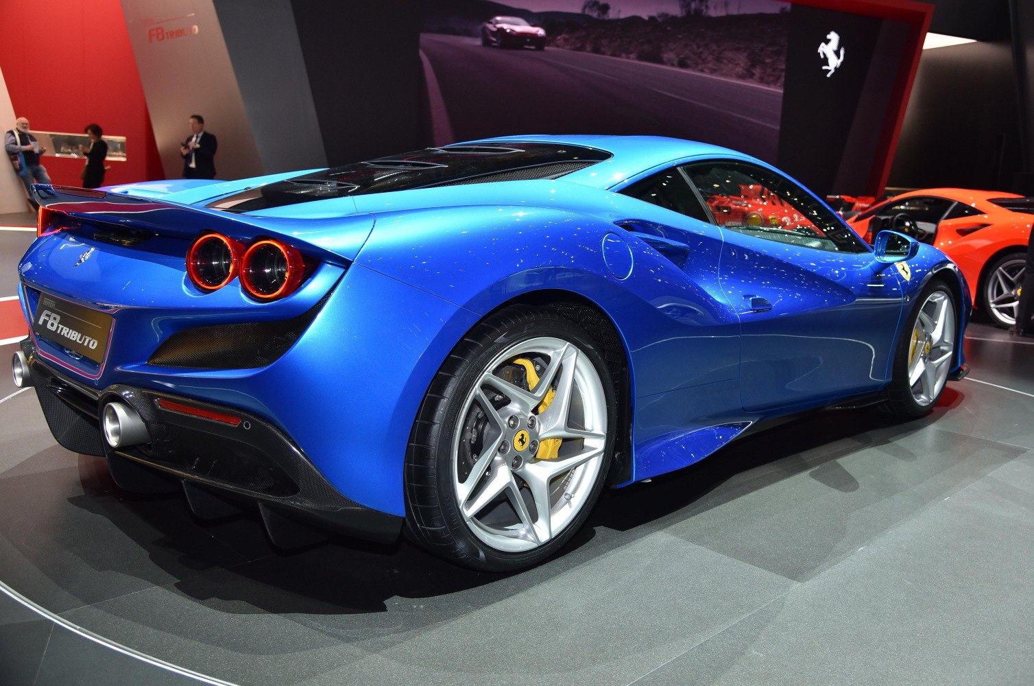 Rear and side view of a blue sports car with round taillights and alloy wheels