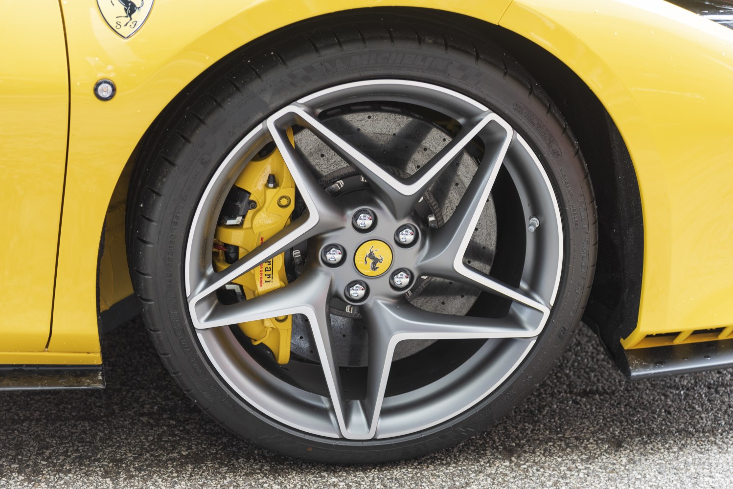 Close-up of star-shaped alloy wheel and yellow brake caliper.