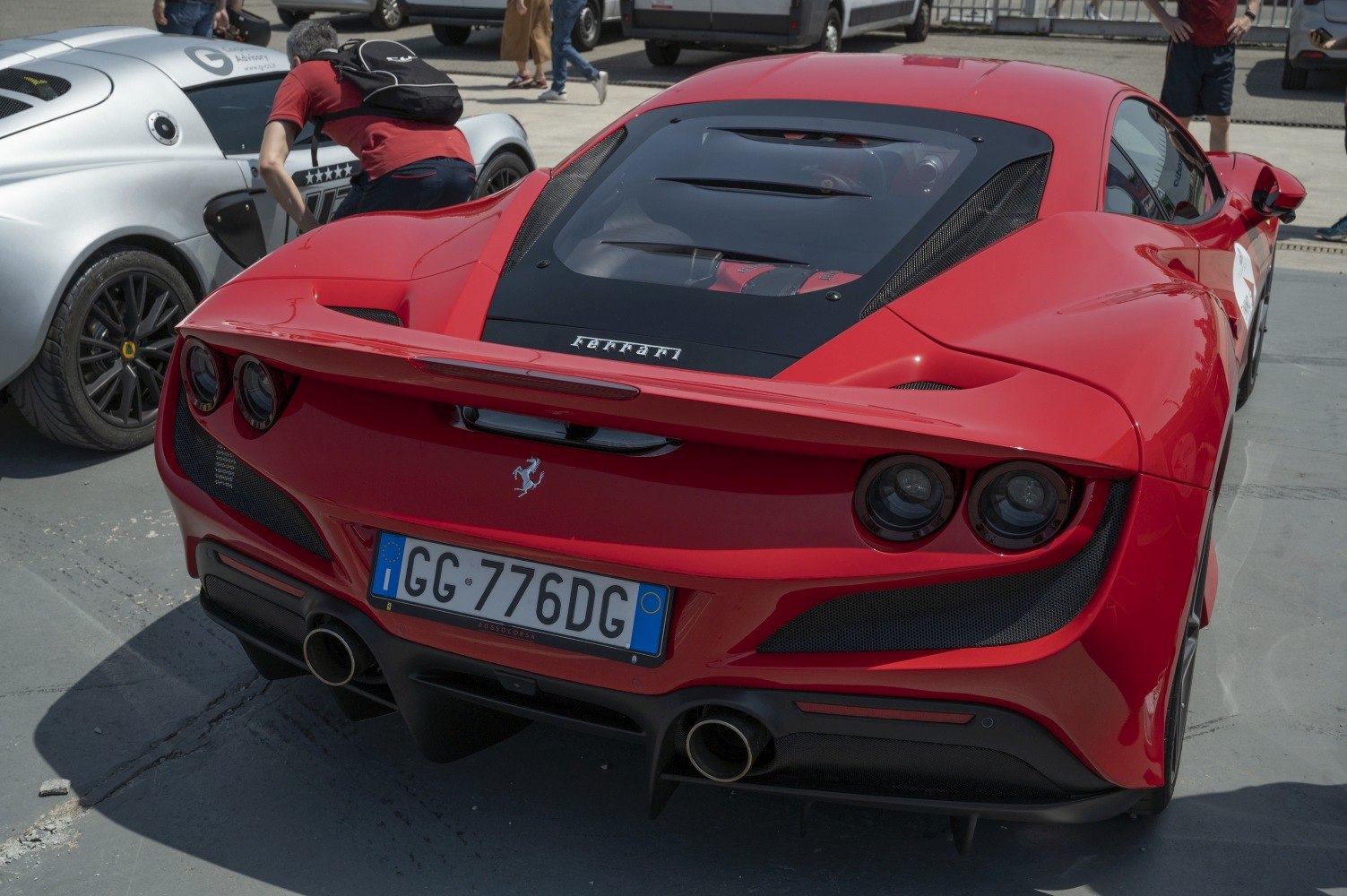 Rear view showing dual circular tail lights, engine visible through glass hood, and dual exhaust pipes.