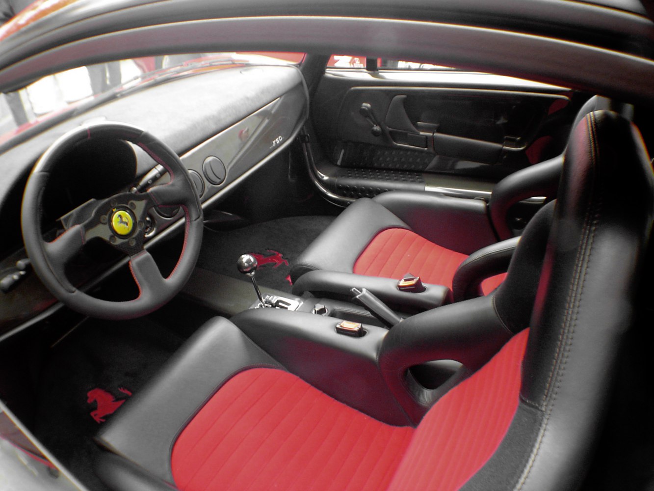 Red and black leather racing seats with classic steering wheel and manual shifter.