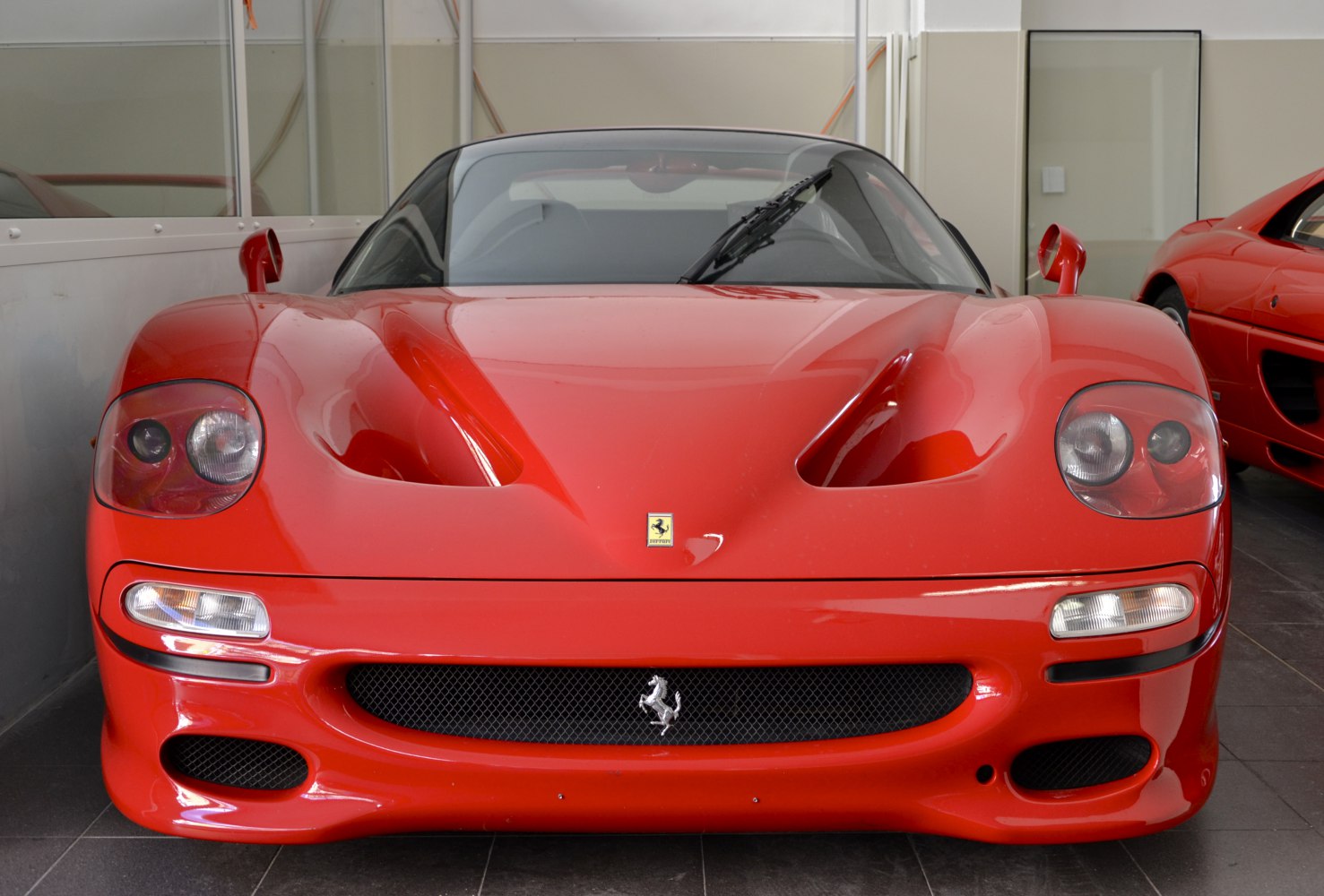 Front view of a red sports car with aerodynamic vents and distinct headlamps