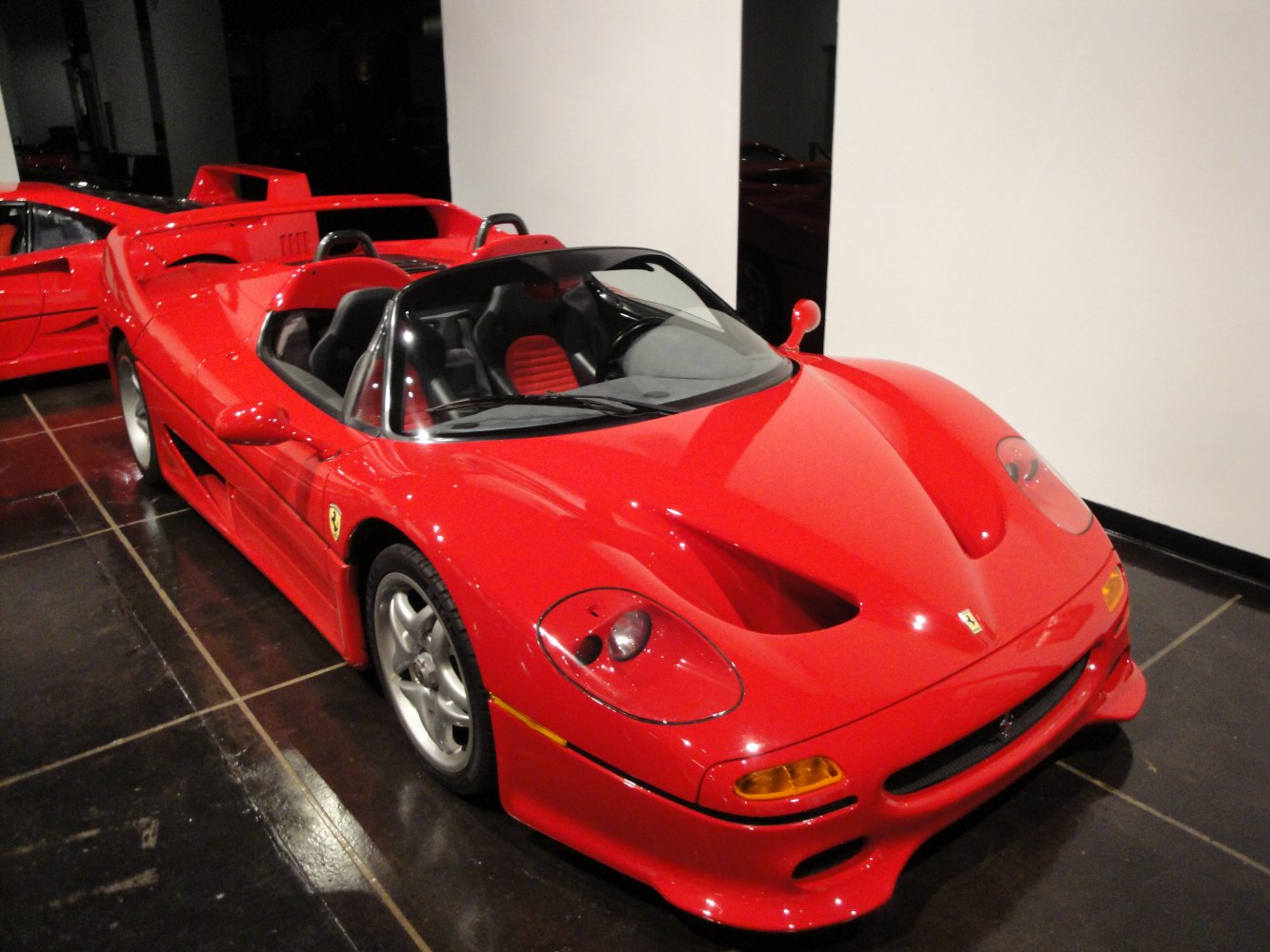 Red mid-engine roadster with aerodynamic curves and open-top design