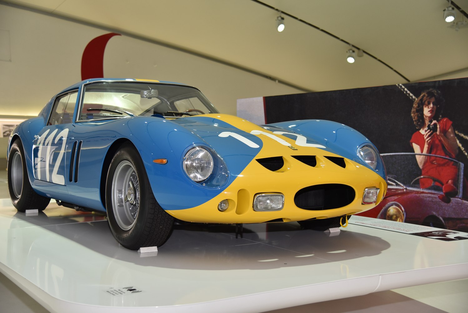 Blue and yellow vintage racing coupe with prominent number on hood and sides.