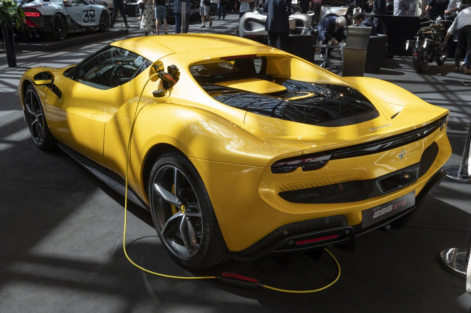 Yellow electric sports car with aerodynamic rear and charging cable