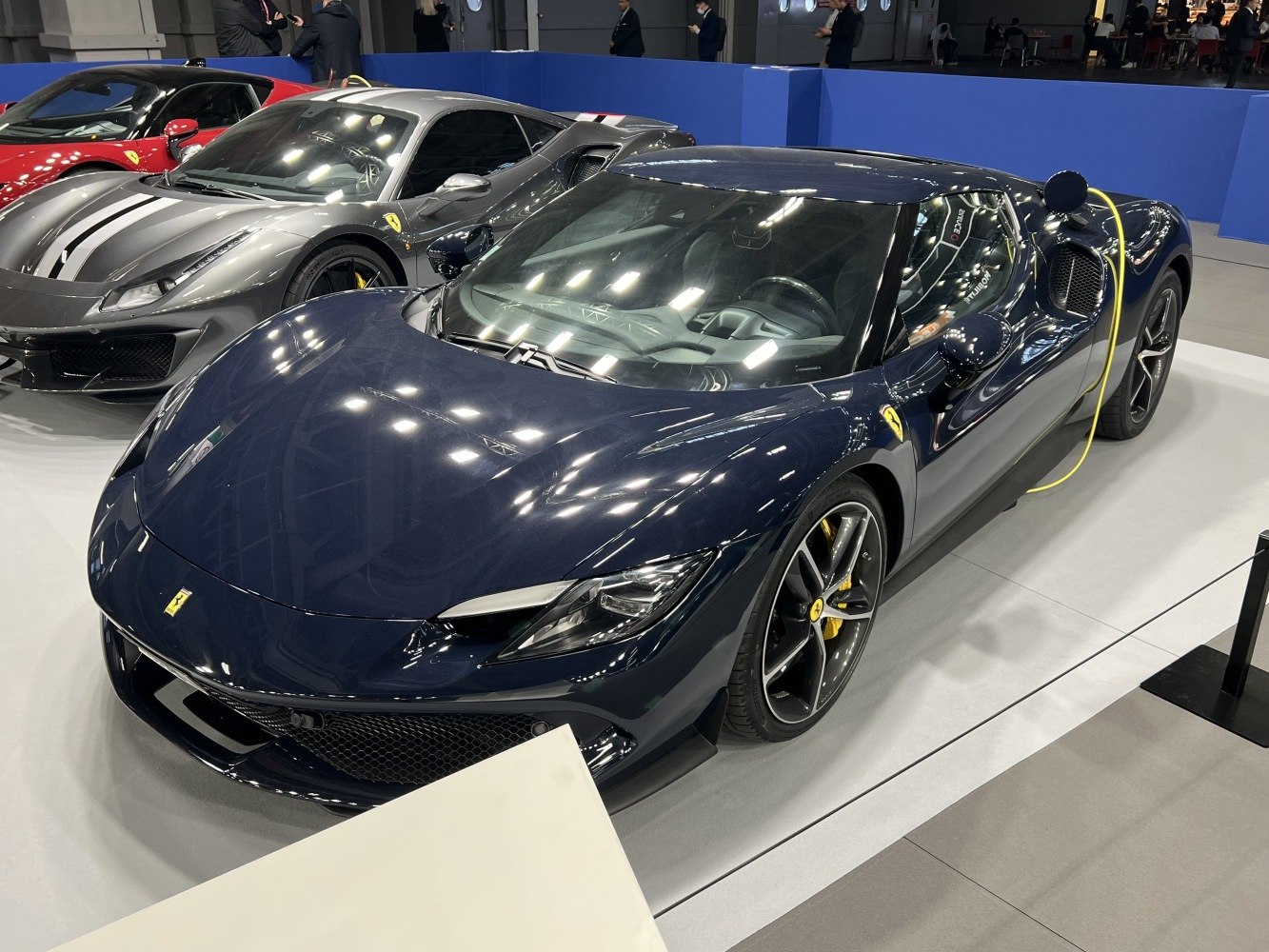 Sleek sports car front with sharp headlights and electric charging cable