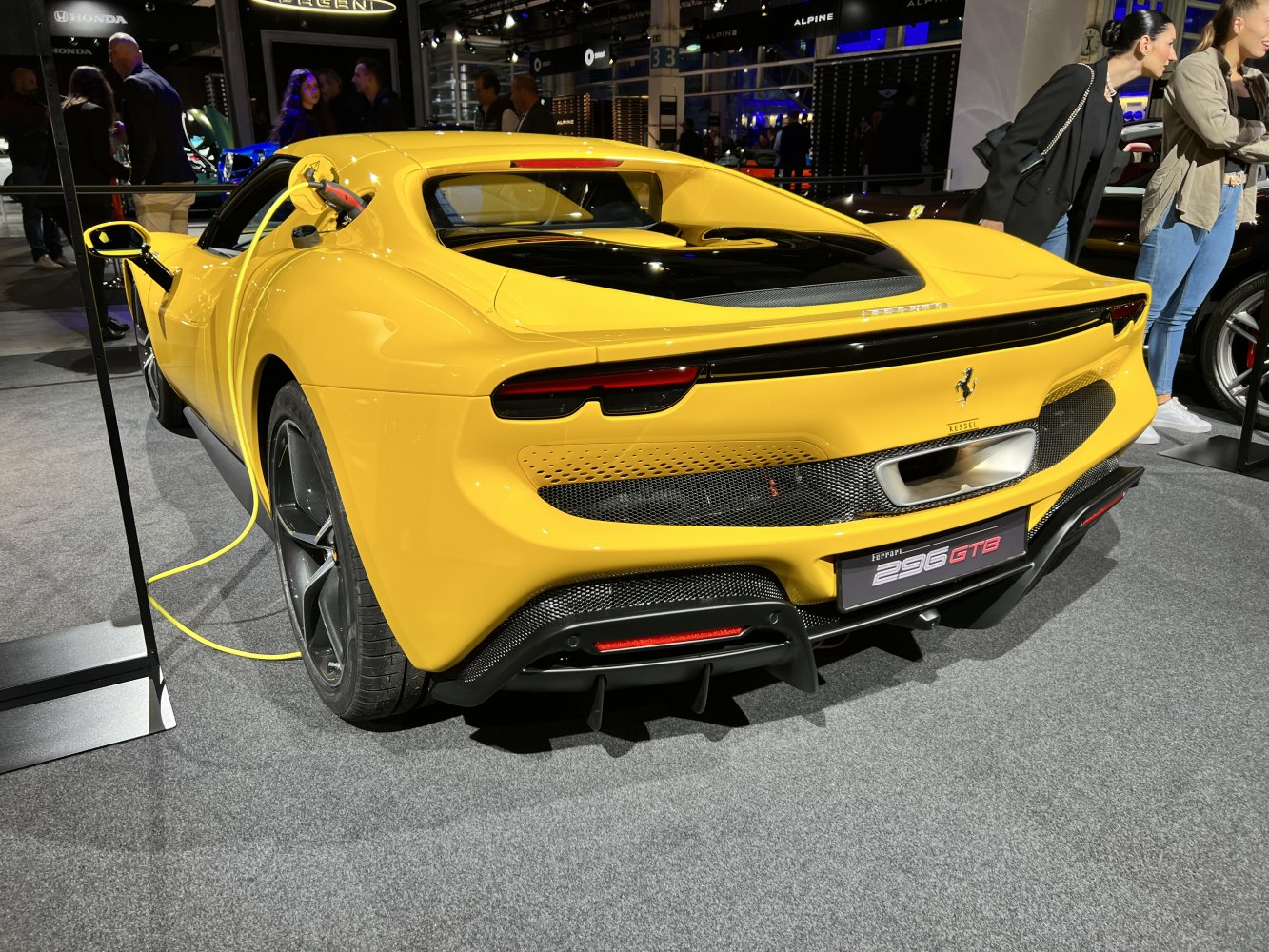 Yellow electric sportscar rear with charging plug and sleek diffuser.