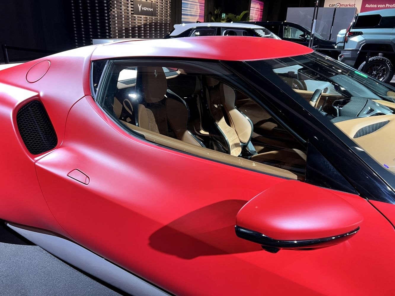 Aerodynamic red sports coupe side profile with visible interior and door mirror