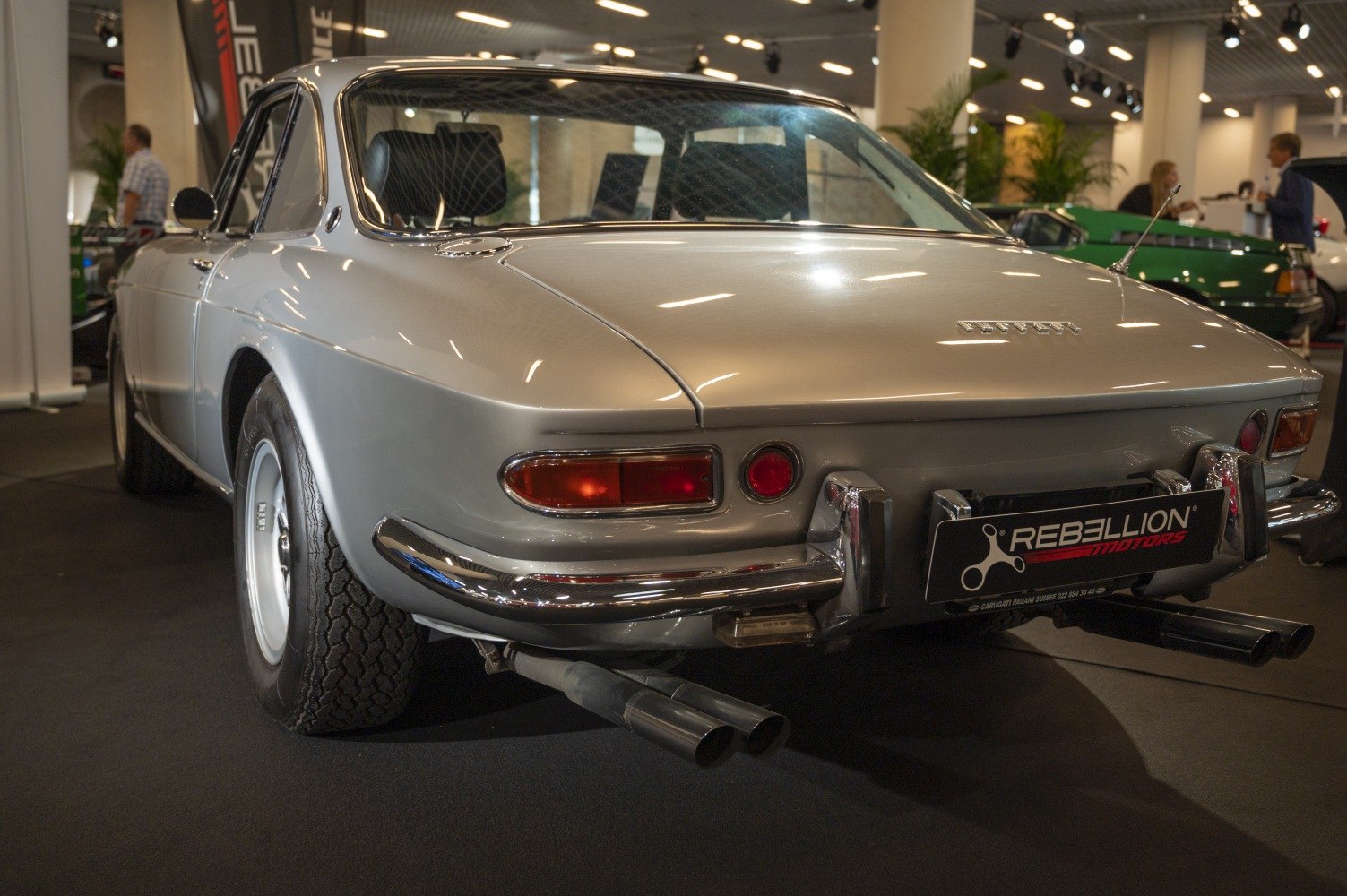 Rear view of vintage coupe with twin exhaust pipes and distinct rear lights.