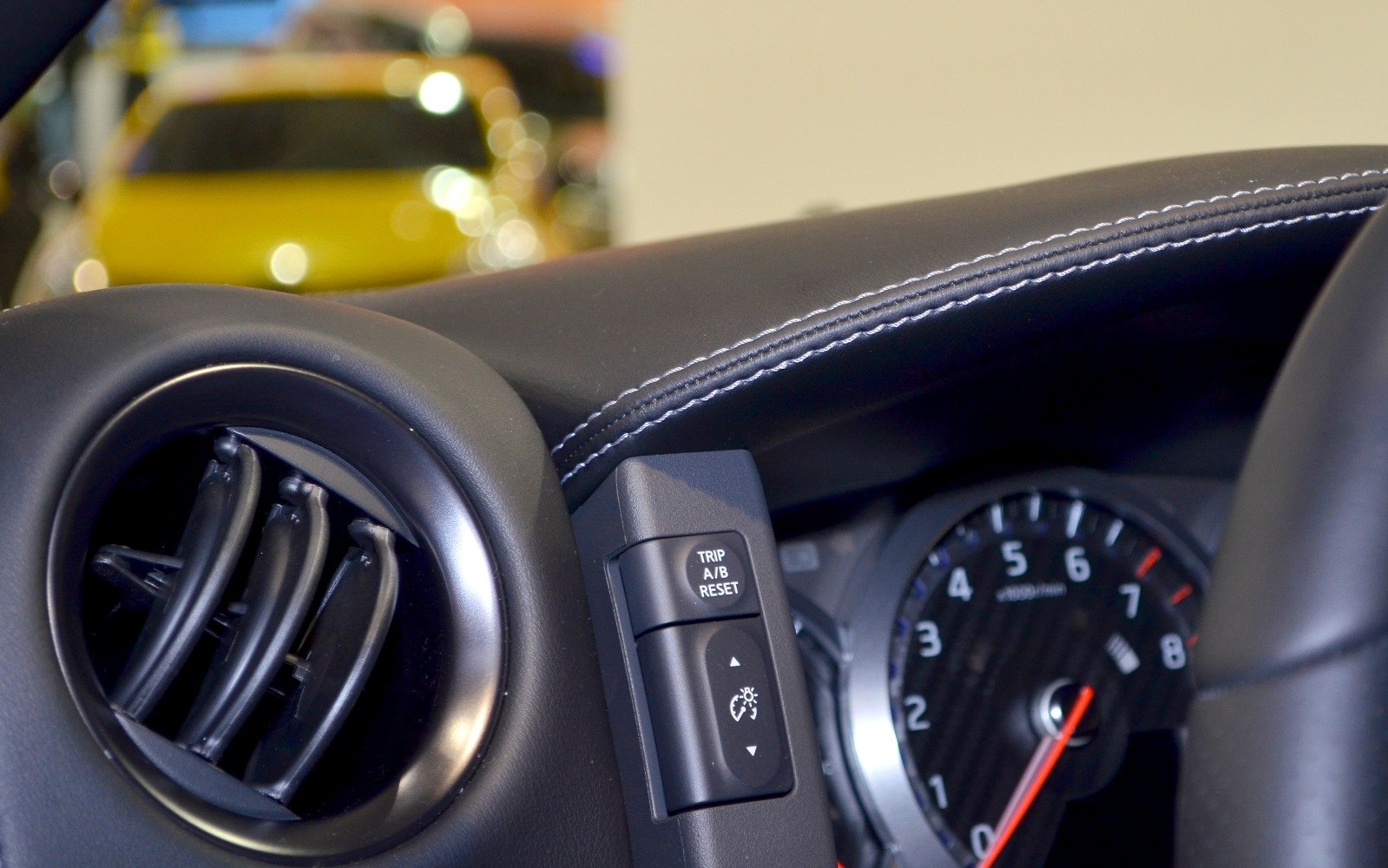 Dashboard air vent, control buttons, and detailed stitching on dashboard