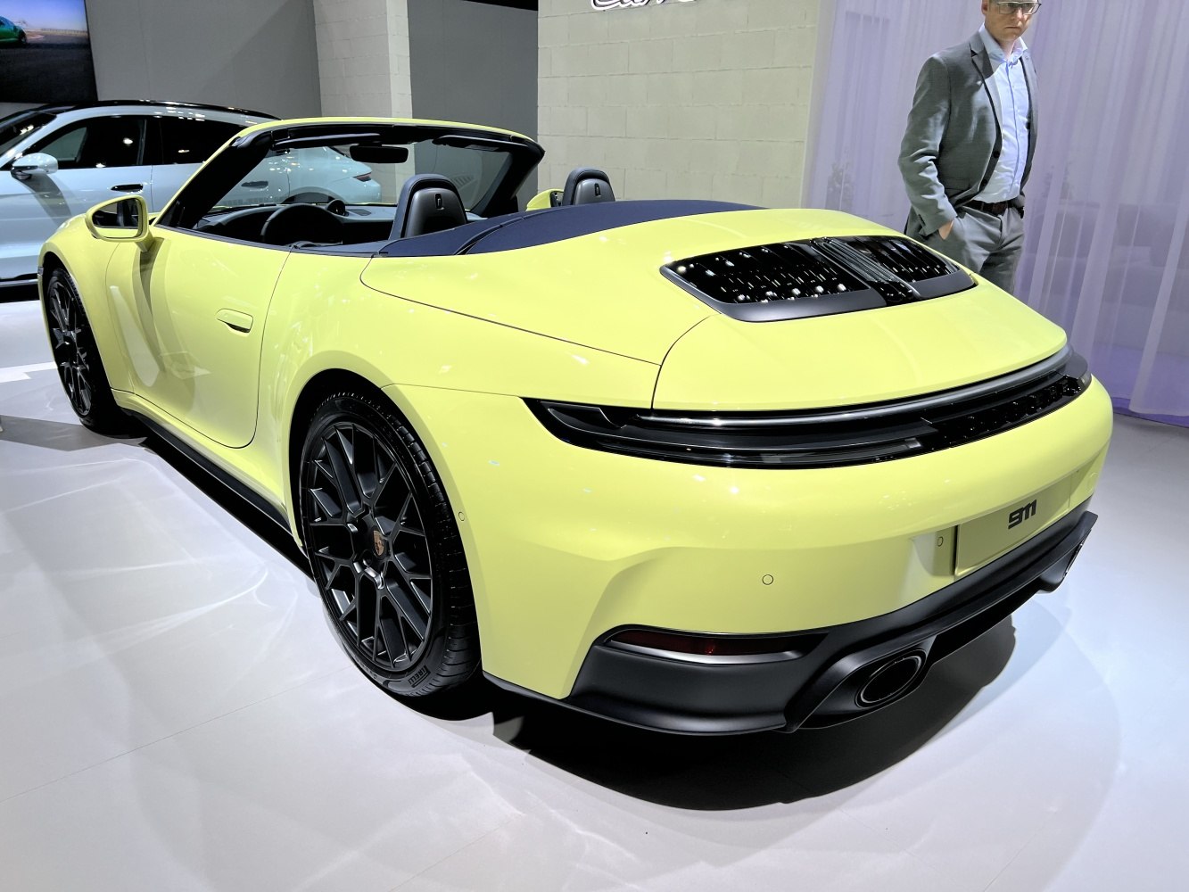 Rear view of a yellow convertible with prominent wheel design and rear light strip.