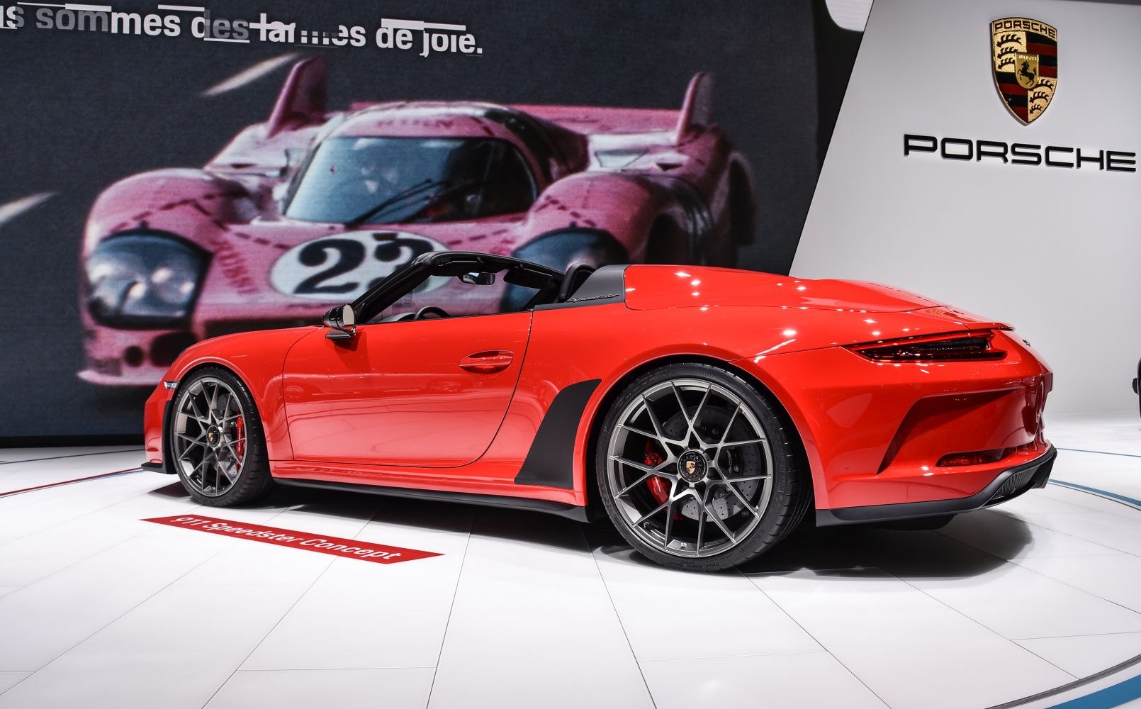 Side profile of red convertible with aerodynamic rear and multi-spoke wheels.