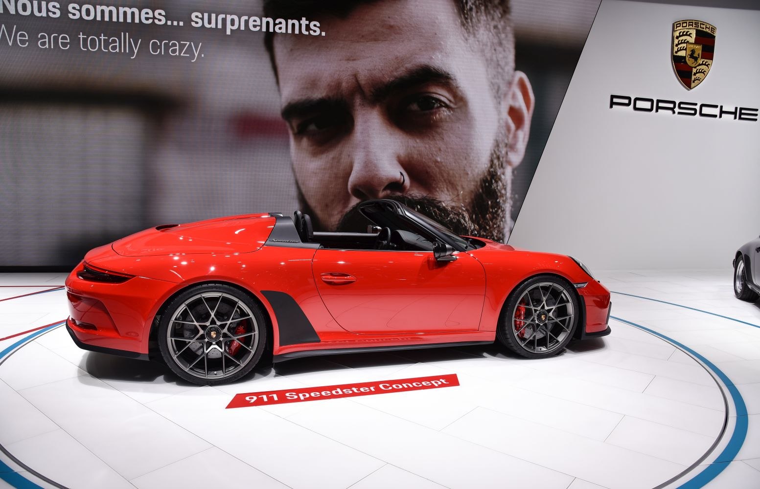 Sleek red open-top roadster with distinctive rear deck and multi-spoke wheels