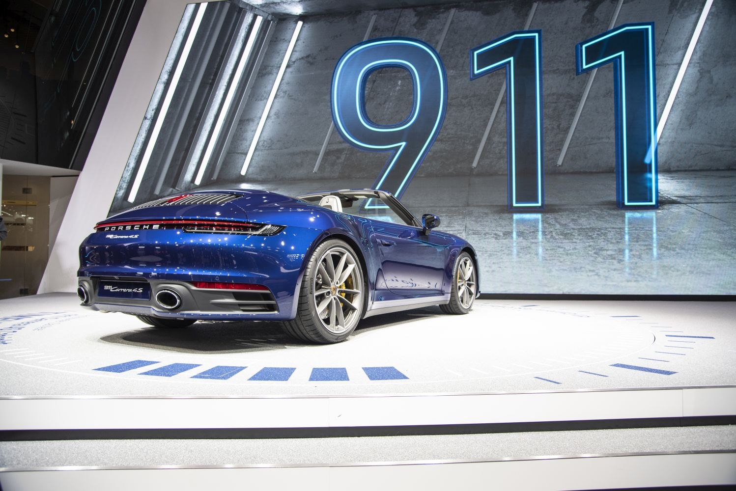 Rear view of blue convertible with distinctive taillight strip and dual exhausts