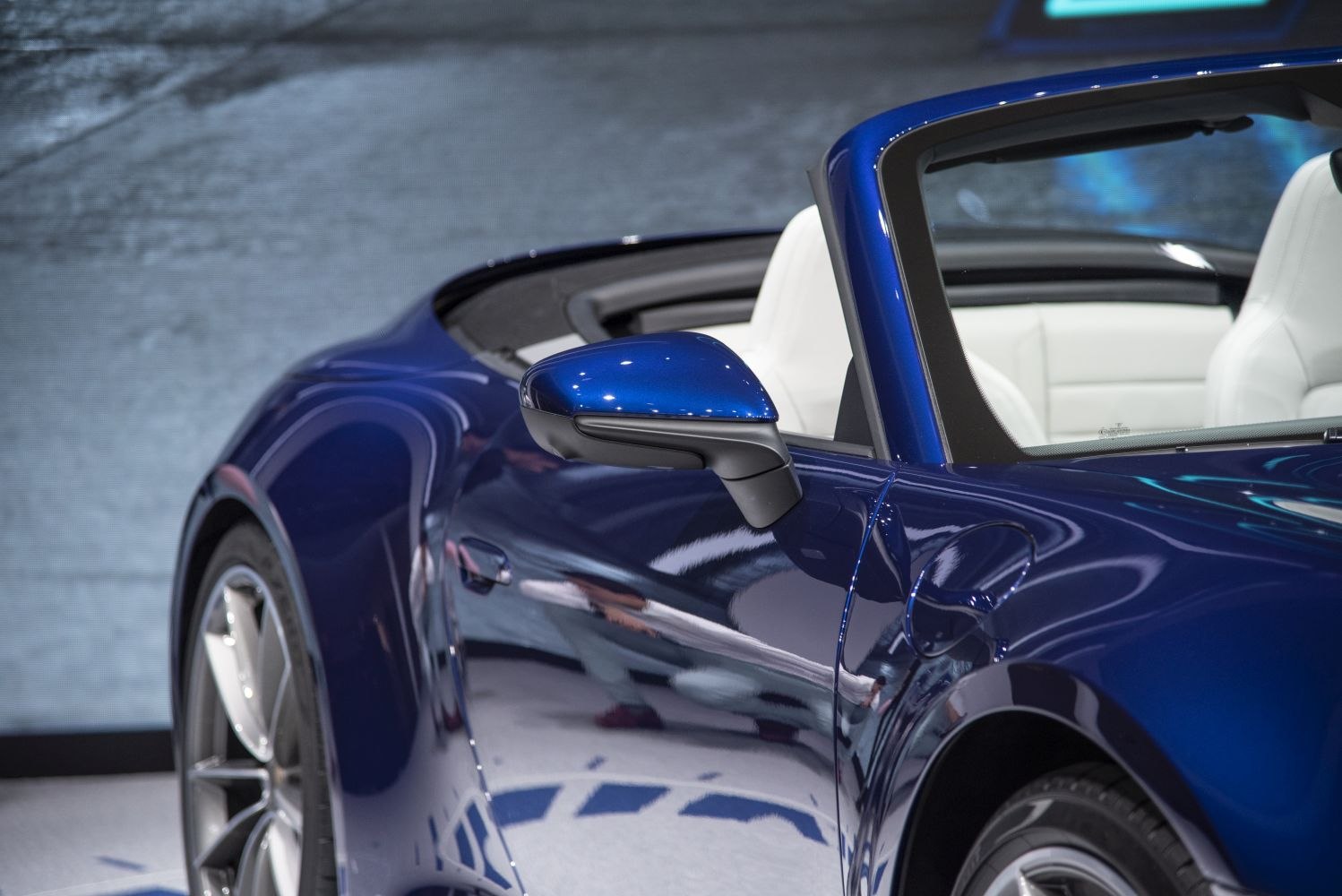 Blue side mirror with white leather seats and glossy exterior paint.