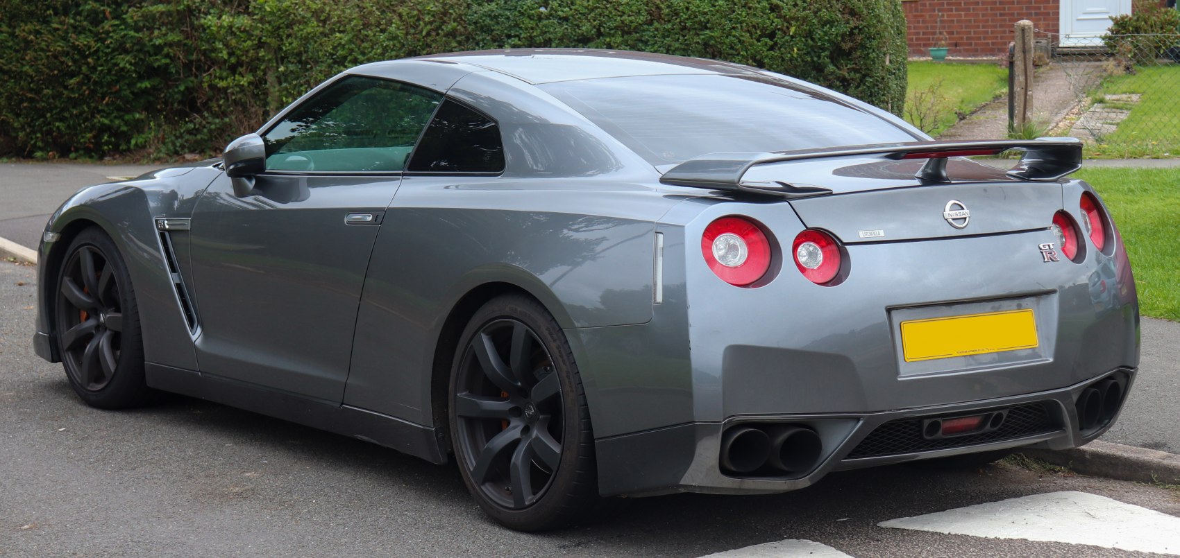 Rear side view with spoiler, round taillights, and sporty wheels